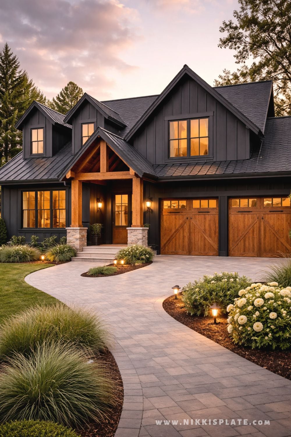 Black modern farmhouse exterior with warm wood garage doors, covered porch, and landscaped walkway at dusk