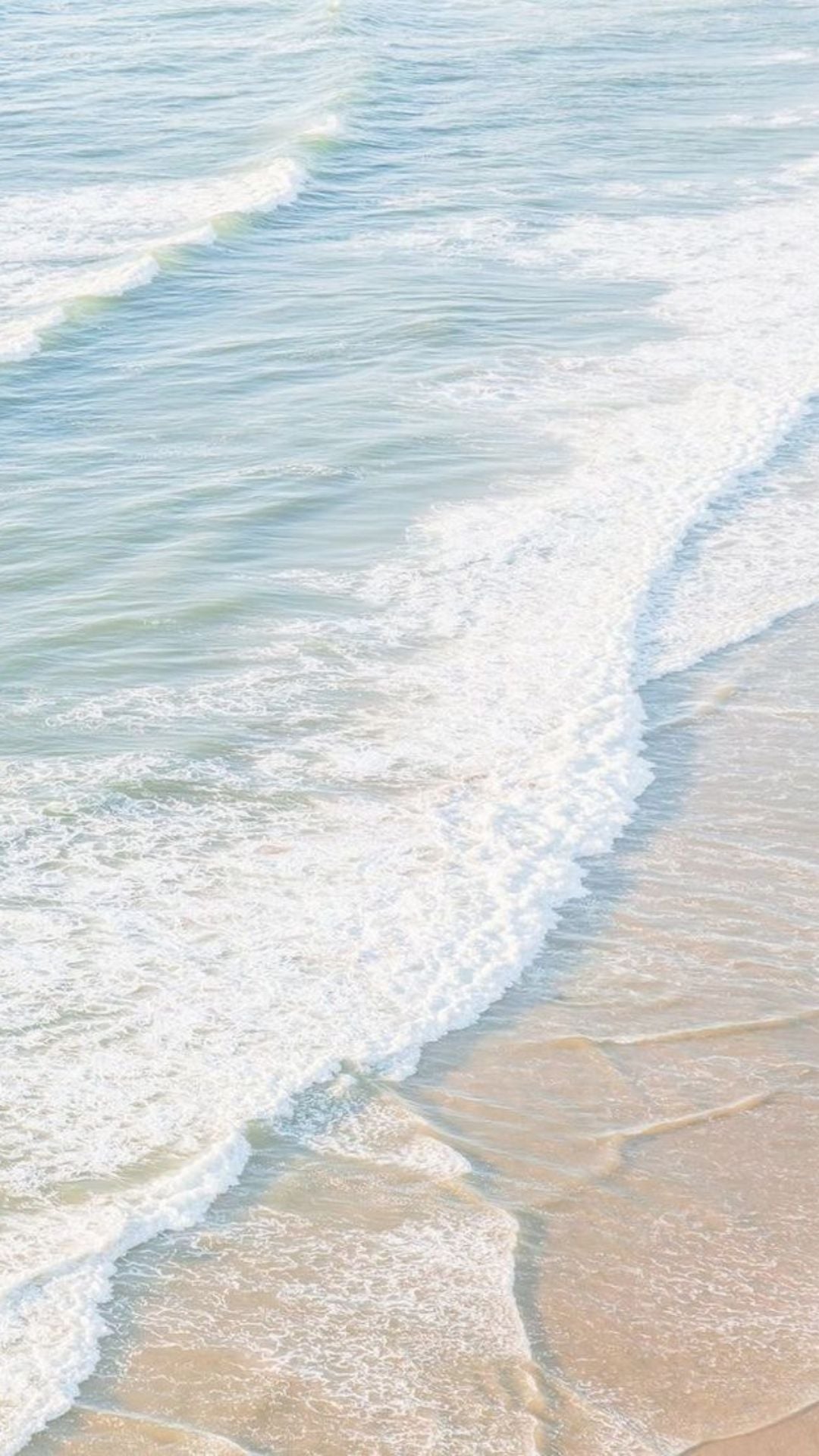 Beach summer iPhone wallpaper with soft blue ocean waves and white sea foam on sandy shore
