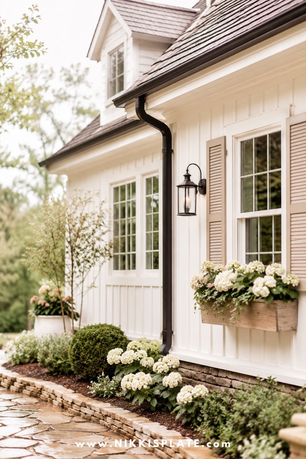Bright farmhouse exterior with a covered entry, fresh white siding, warm wood accents, soft landscaping, and rain-friendly updates that protect the home.