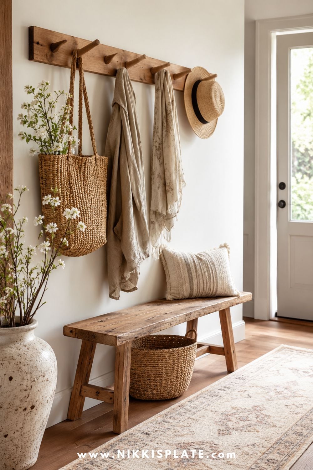 Simple wooden peg rail in a farmhouse entryway holding bags, scarves, and hats above a rustic bench.