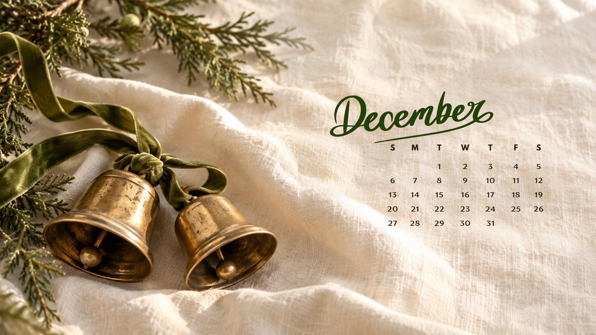 December 2026 desktop calendar with aged brass Christmas bells and olive velvet ribbon on cream linen.