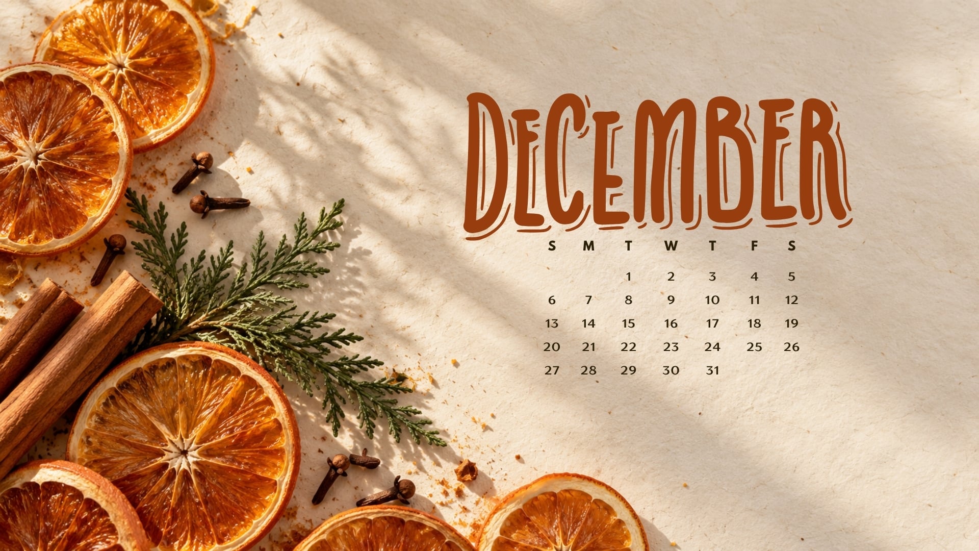 December 2026 desktop calendar with dried orange slices, cinnamon sticks, cloves and a cedar sprig.