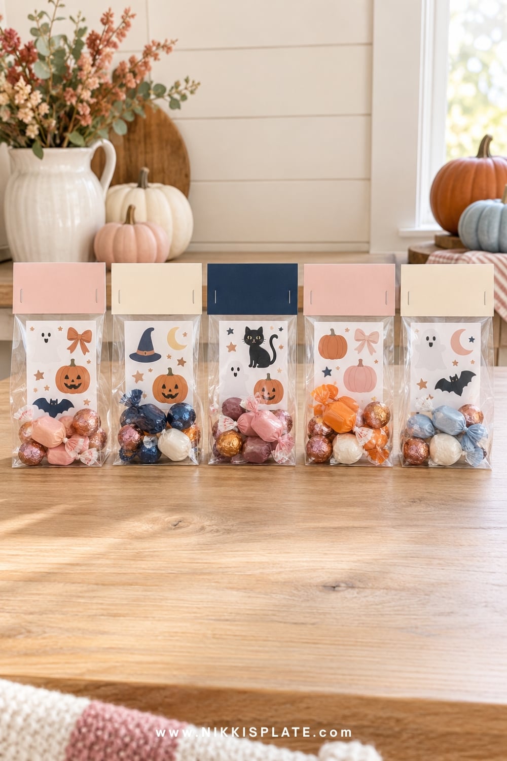 Clear Halloween favour bags filled with treats and topped with folded cards.