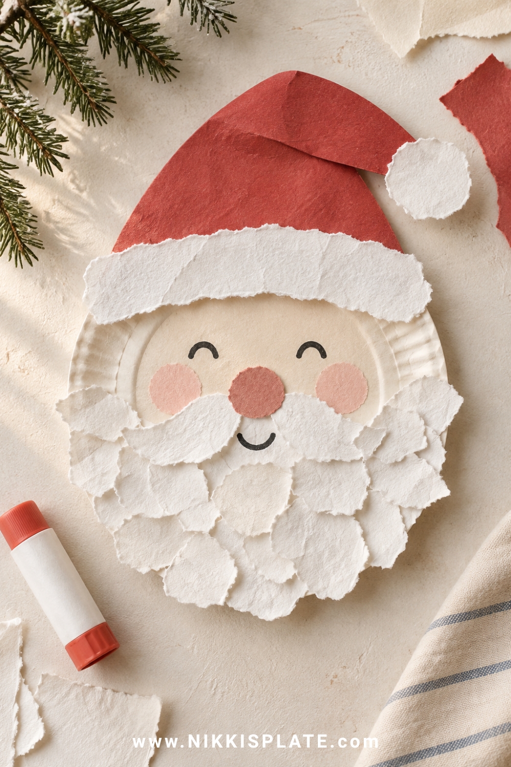 Paper plate Santa craft with a red paper hat, rosy cheeks and layered torn-paper beard.