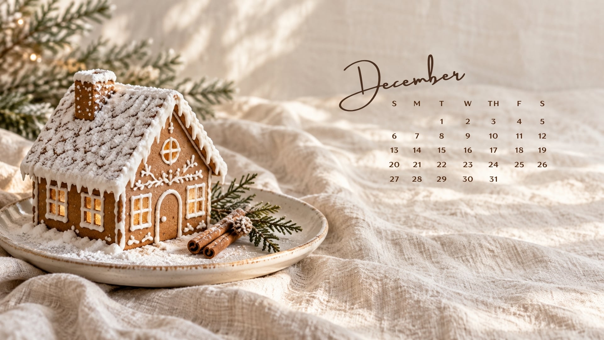 December 2026 desktop calendar with a gingerbread cottage on cream linen beside cinnamon sticks.