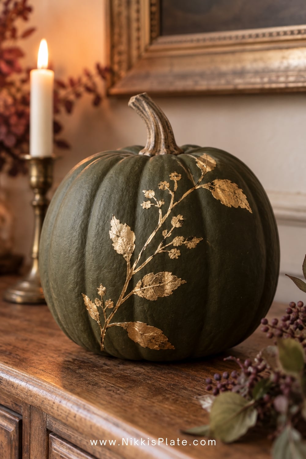 Deep olive pumpkin decorated with delicate gold-leaf botanical branches.