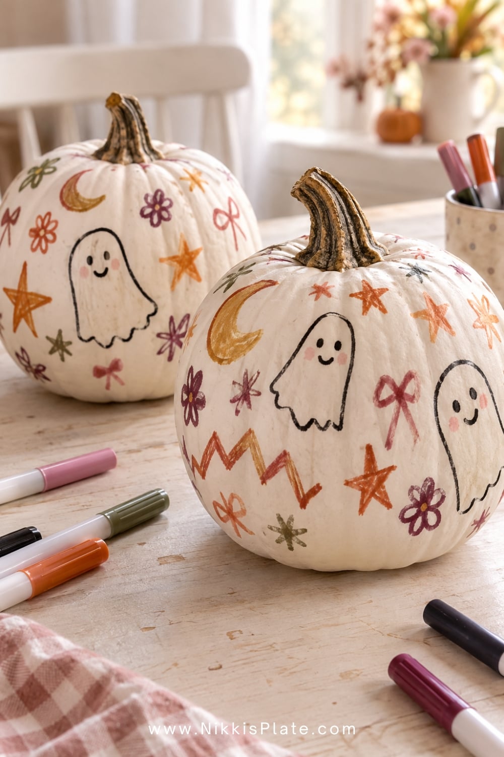 White faux pumpkins covered with colourful child-drawn ghosts, stars, flowers and bows.