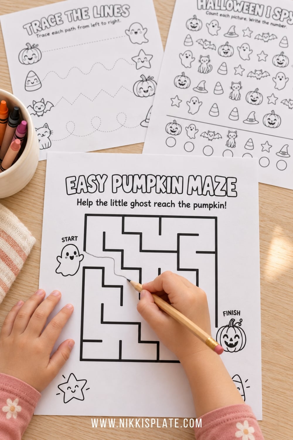 Child completing a printable Halloween maze with a pencil beside crayons and activity sheets.