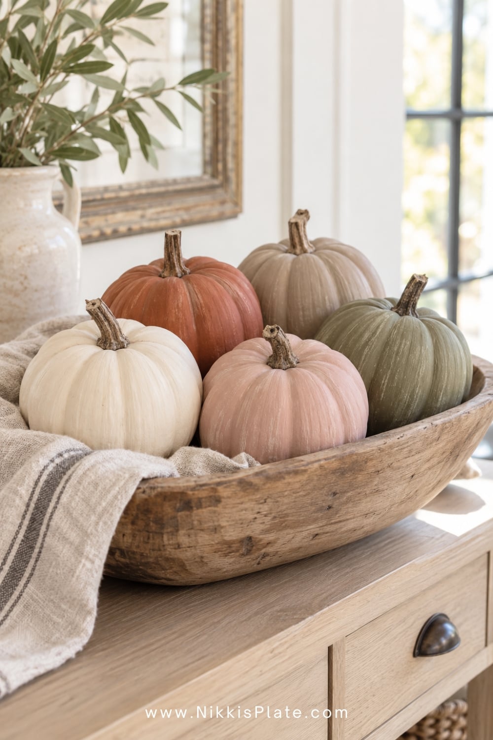 Matte cream, blush, rust and olive no-carve pumpkins arranged in a wooden bowl.