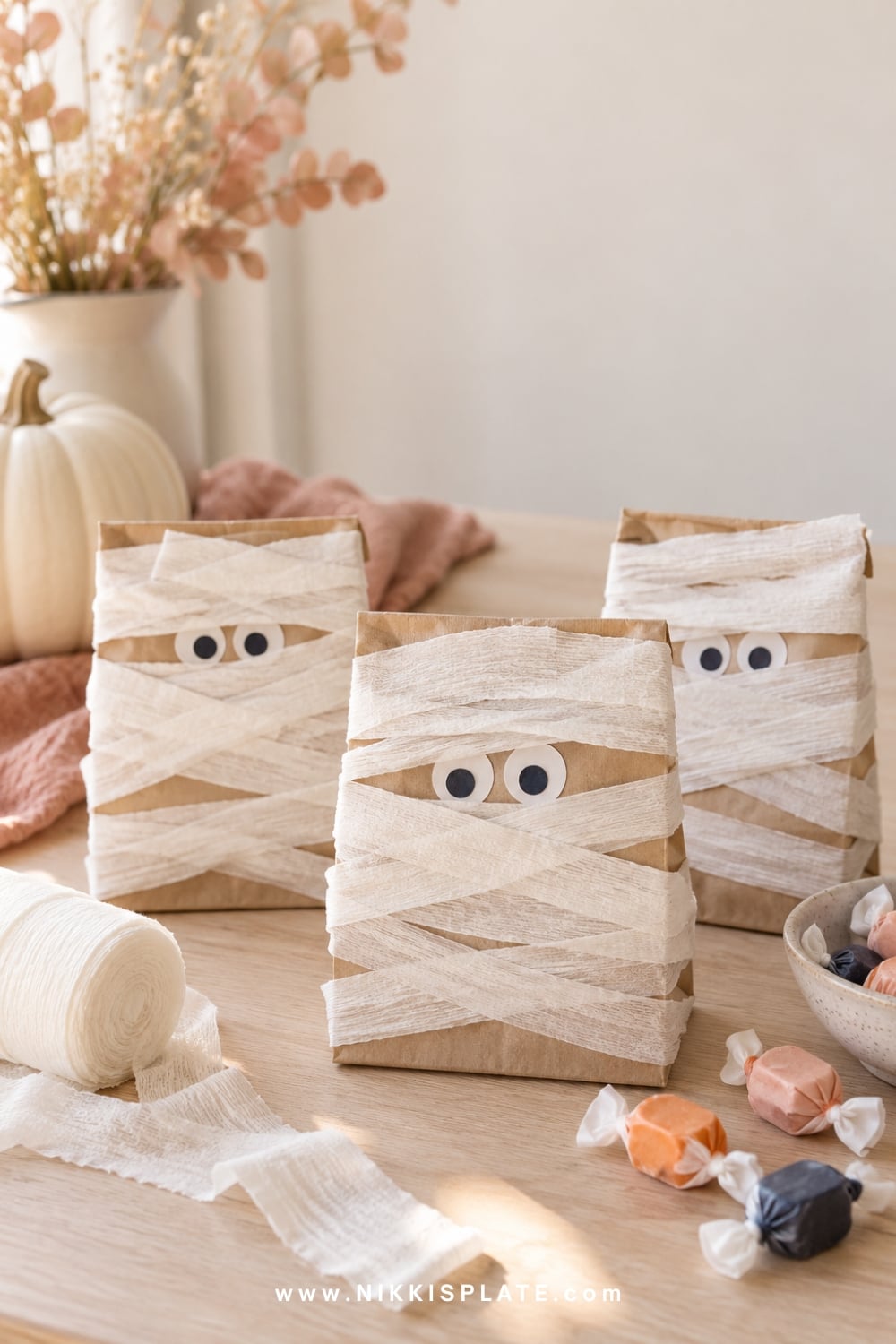 Kraft Halloween treat bags wrapped like friendly mummies with paper eyes.