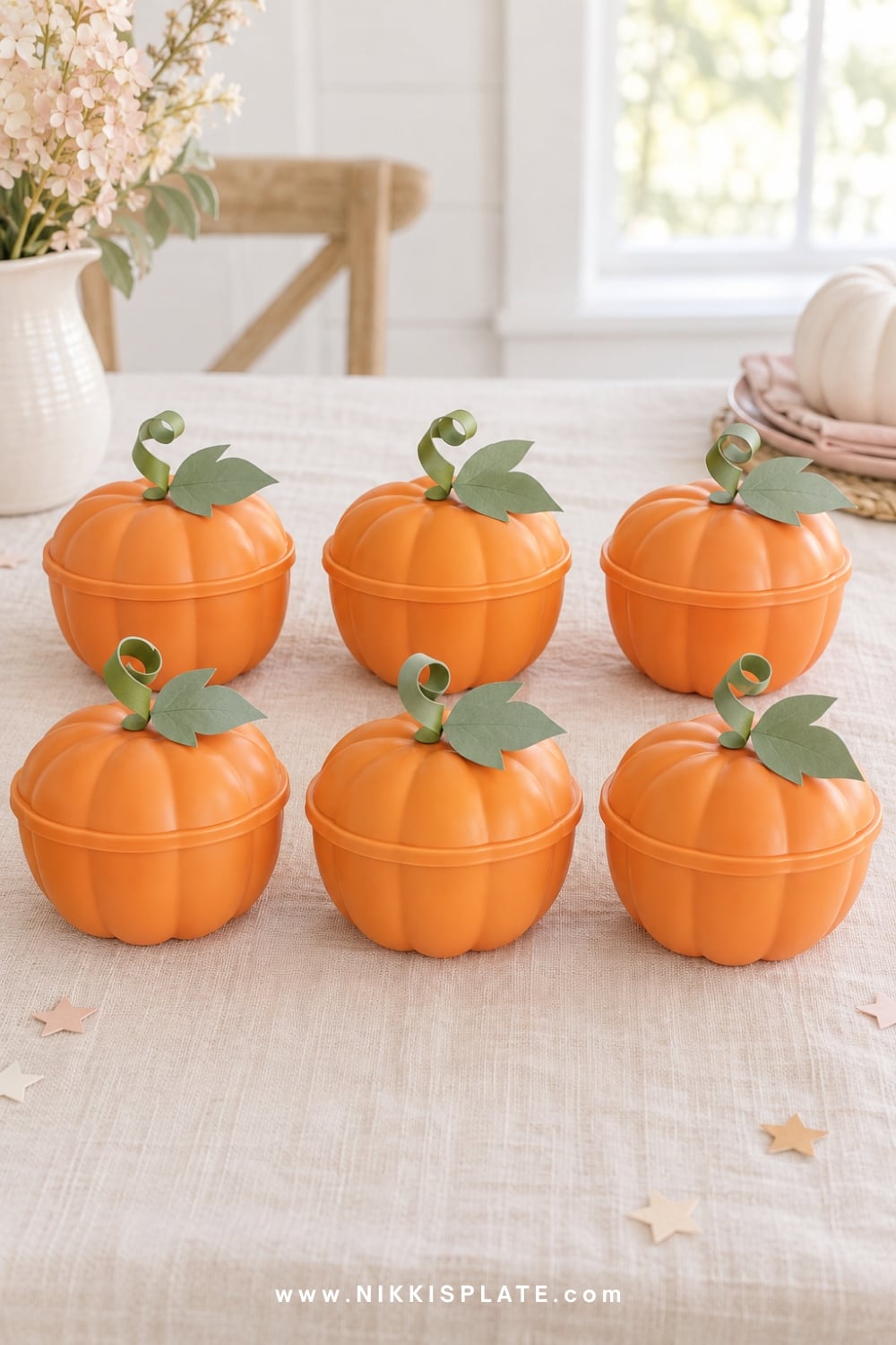 Orange lidded snack cups styled as small pumpkins with paper leaves.