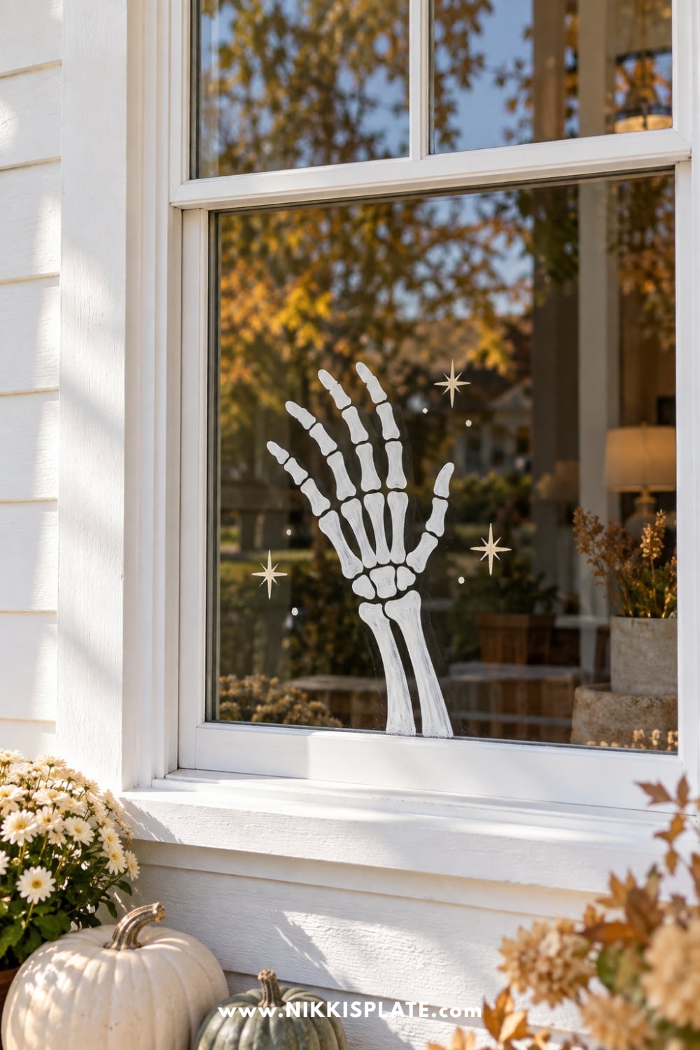 White skeleton hand painted in a friendly wave on a front window.