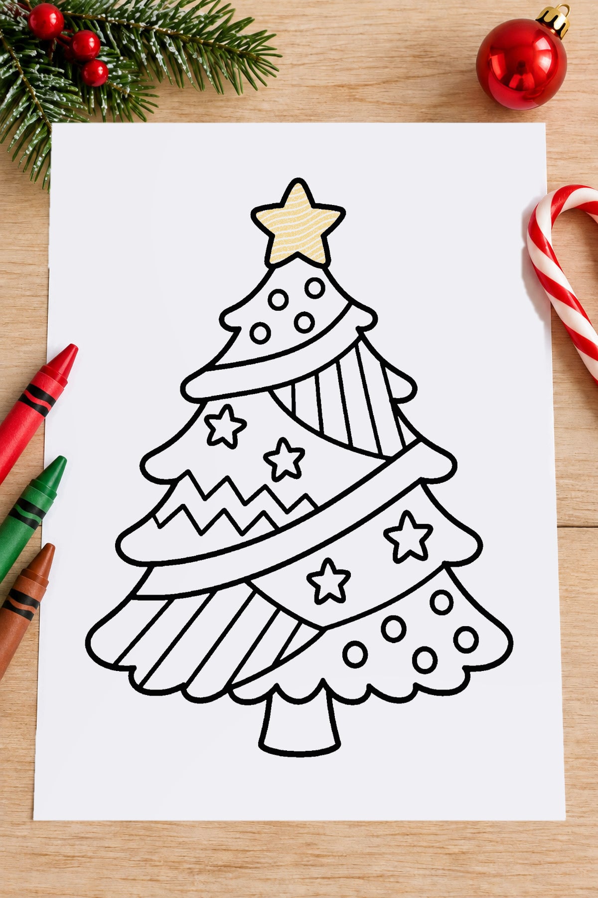 Patterned Christmas tree coloring page featuring stars, stripes, zigzags, and polka dots, displayed with crayons and Christmas greenery.