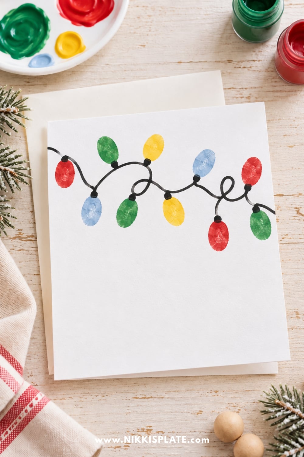 Easy fingerprint Christmas lights craft with colorful red, green, yellow, and blue painted fingerprints along a black string of lights.