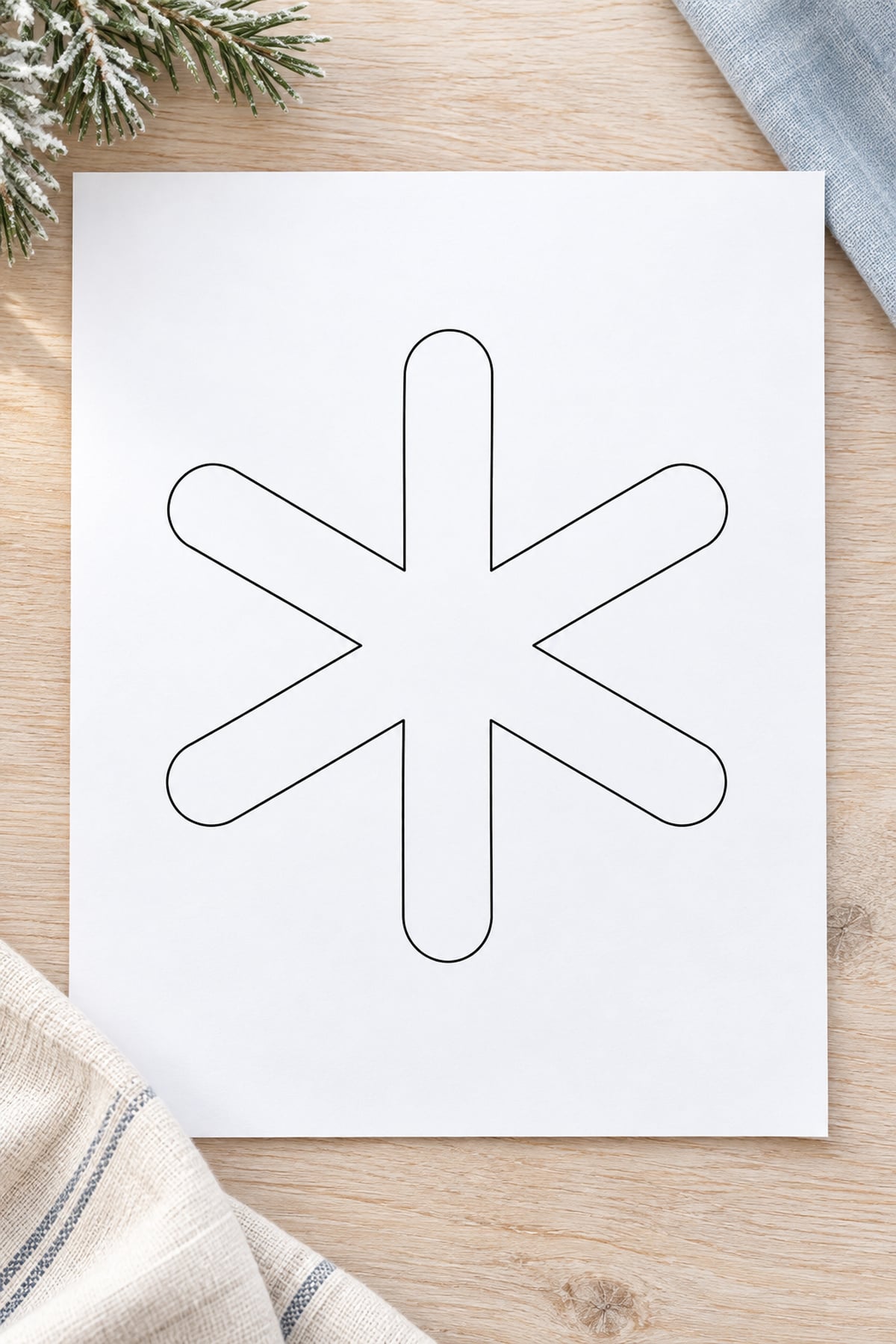 Rounded-tip snowflake template on white paper with ivory linen and a pale blue fabric accent.