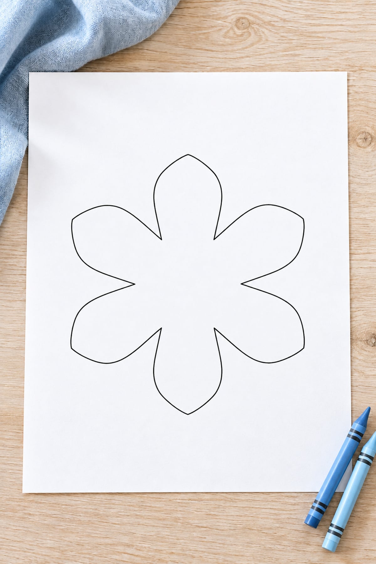 Six-petal snowflake template printed on white paper with two blue crayons.