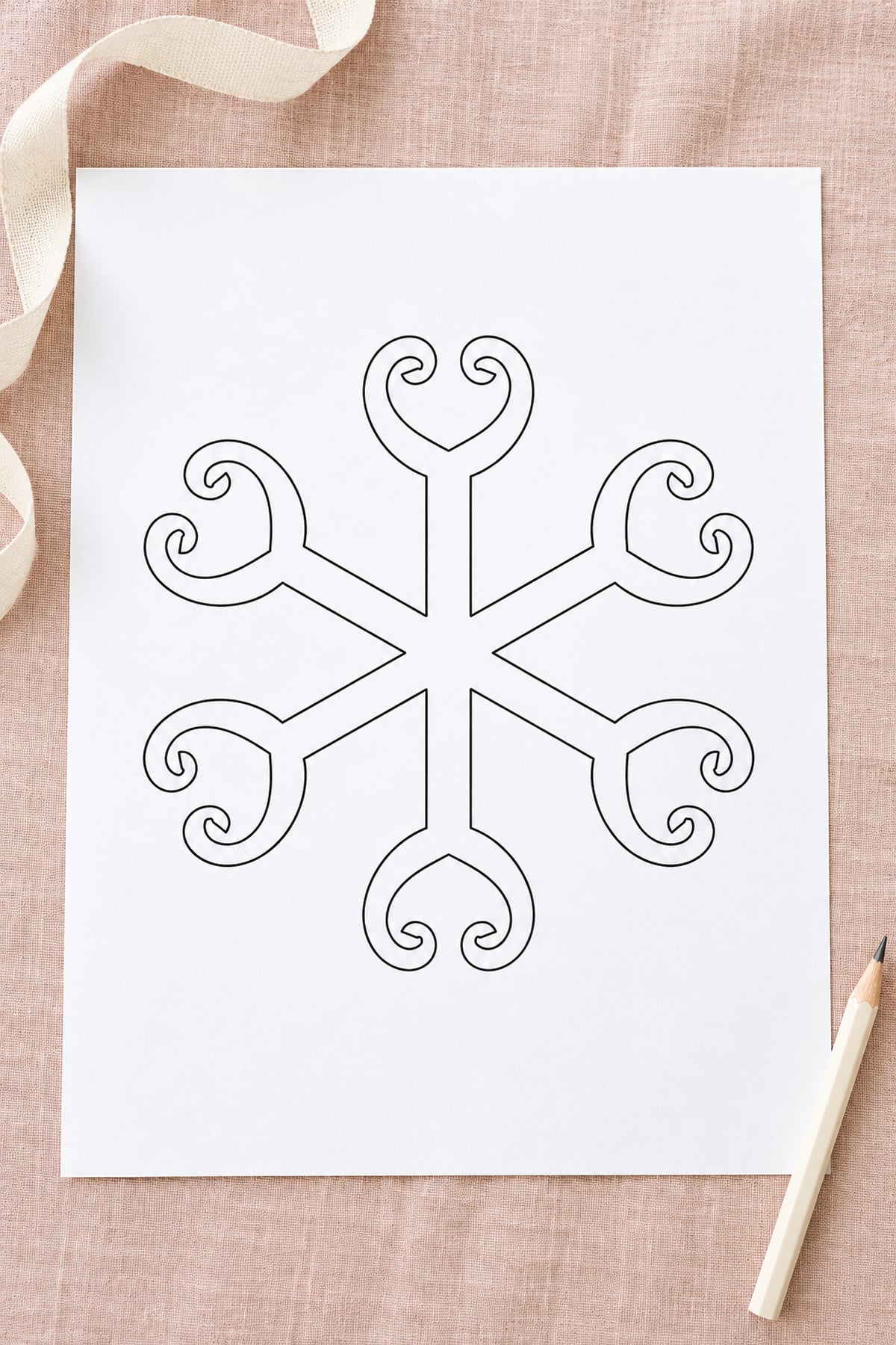 Scroll-tip snowflake template with curled branches on blush linen, styled with cream ribbon and an ivory pencil.