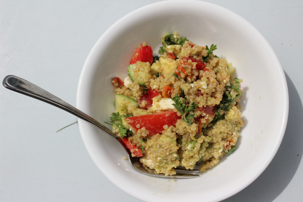 Avocado and Greek Quinoa Salad with lemon dijon mustard dressing. Red peppers, tomatoes. avocado, quinoa, cucumber. Gluten free and dairy free options. Bowl and fork