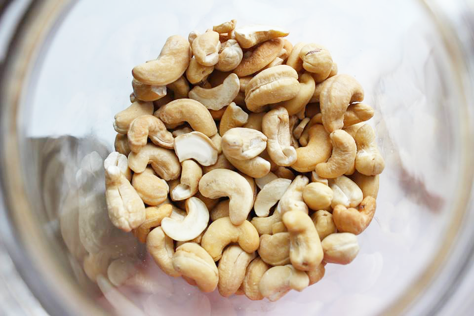Looking down into a blender of cashews for vegan chocolate cheesecake bites. 