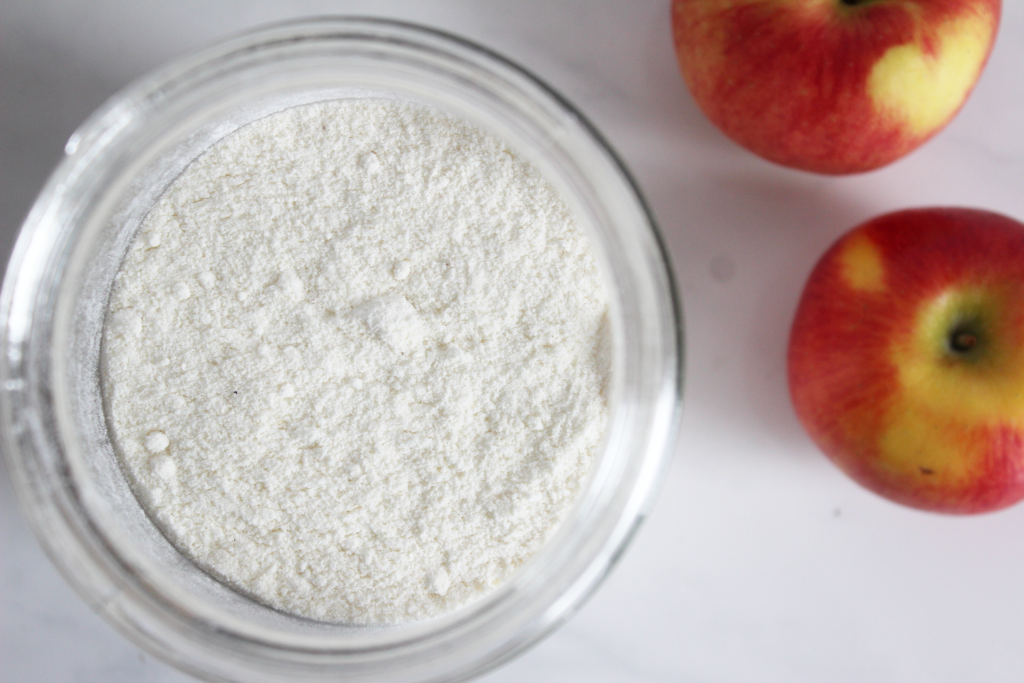 Container of flour with two red apples beside it