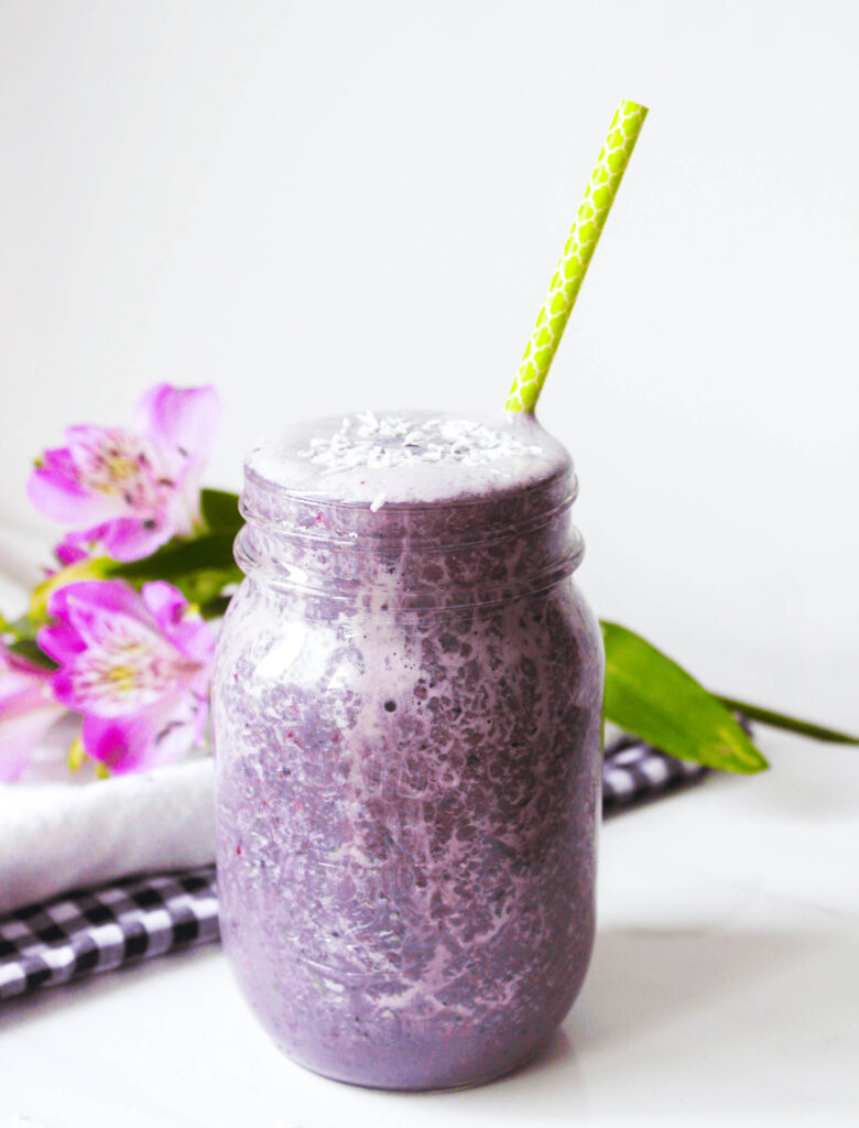 Berry Lemon Smoothie; side view of purple drink smoothie with berries. Green straw, mason jar, cold beverage.