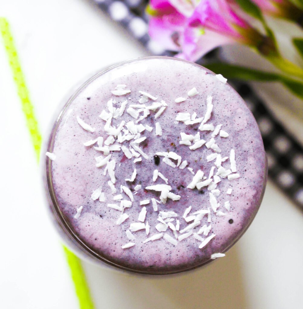 Top photo of berry lemon smoothie. coconut flakes on top. Vegan and dairy free purple drink. Cold beverage 