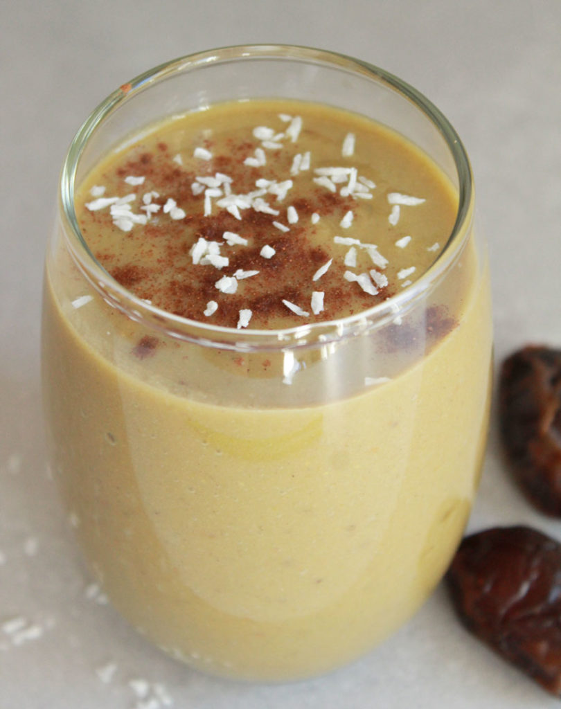 Vegan Pumpkin Pie Protein Smoothie in round glass sprinkled with coconut and cinnamon