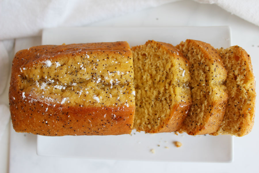 Large Lemon Poppy seed Loaf cut into slices on white plate- Vegan and Gluten Free