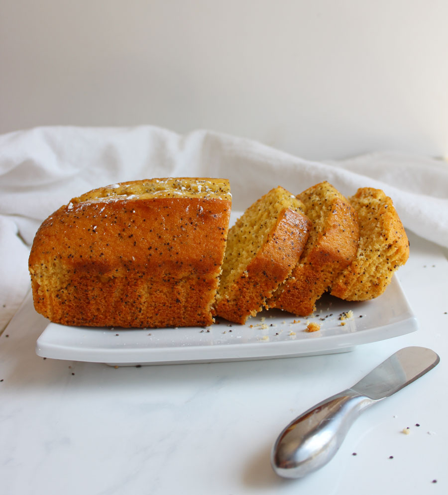 Large Lemon Poppy seed Loaf cut into slices on white plate- Vegan and Gluten Free