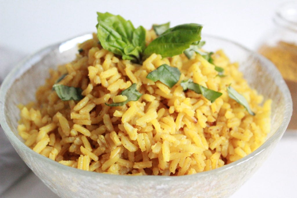 Golden rice with Basil leaves in a bowl. Easy curry rice recipe.