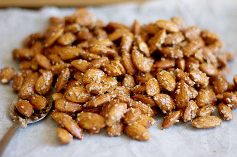 Pile of Honey and Hemp Roasted Almonds on parchment paper - A sweet healthy snack that is packed with natural protein. {Gluten Free & Dairy Free} www.nikkisplate.com