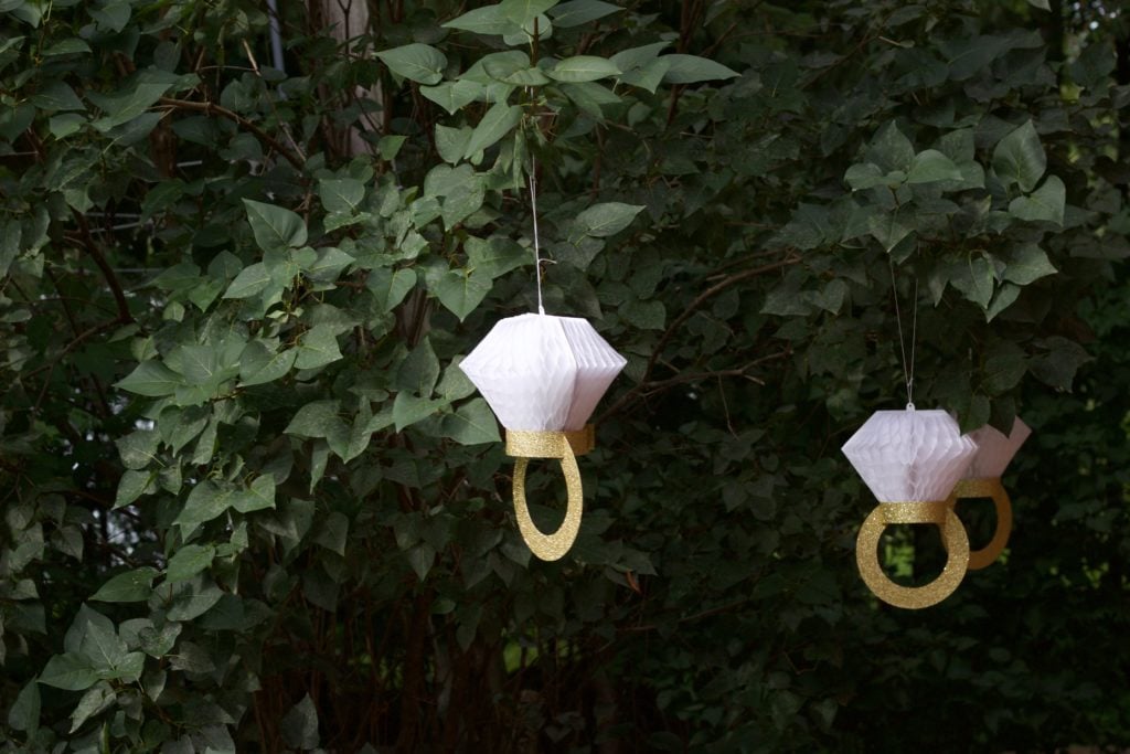 Paper engagement ring decorations hung from the trees at Nikki's engagement party