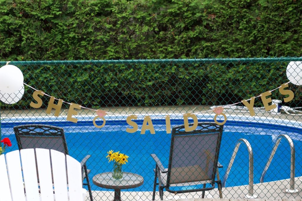 Nikki's engagement party decor featured a "She Said Yes" banner hung on the fence near the pool.