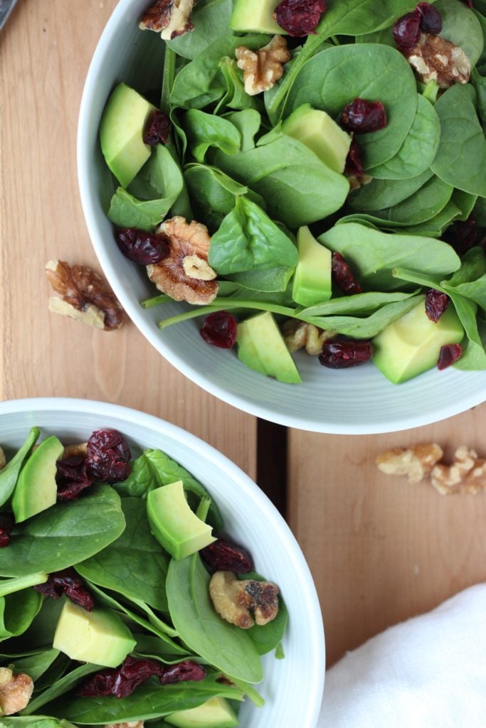 This cranberry walnut salad is topped with fresh avocado and a sweet and tangy honey ginger dressing