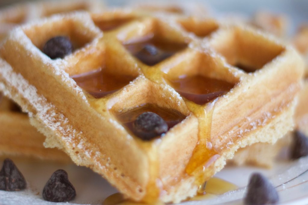 Gluten Free and Dairy Free Belgian Waffles topped with maple syrup and vegan chocolate chips