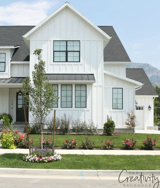 The black trim and dark roof shingles on this farmhouse style home really makes the white siding pop