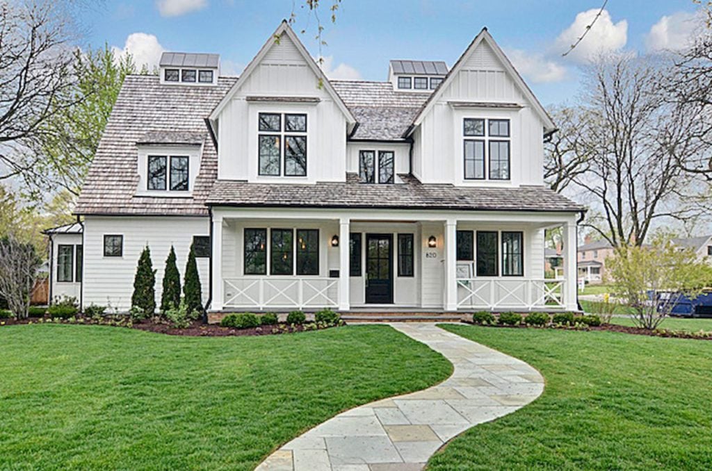 The white siding with the dark shingled roof on this farmhouse style home exterior is perfectly rustic