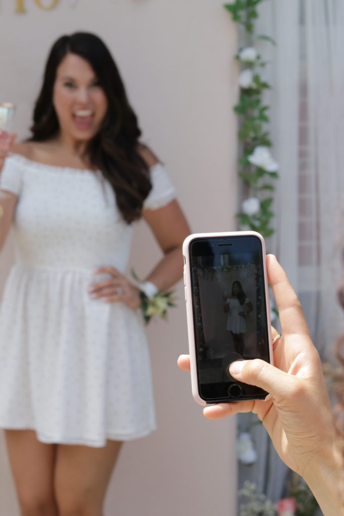 Taking many photos in front of my DIY bridal shower backdrop at my outdoor bridal shower!