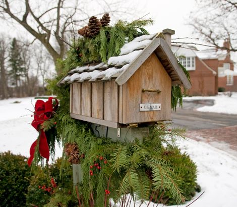 This snow-covered Christmas mailbox is decked out with fresh pine tree branches, pine cones, and bright holly berries 