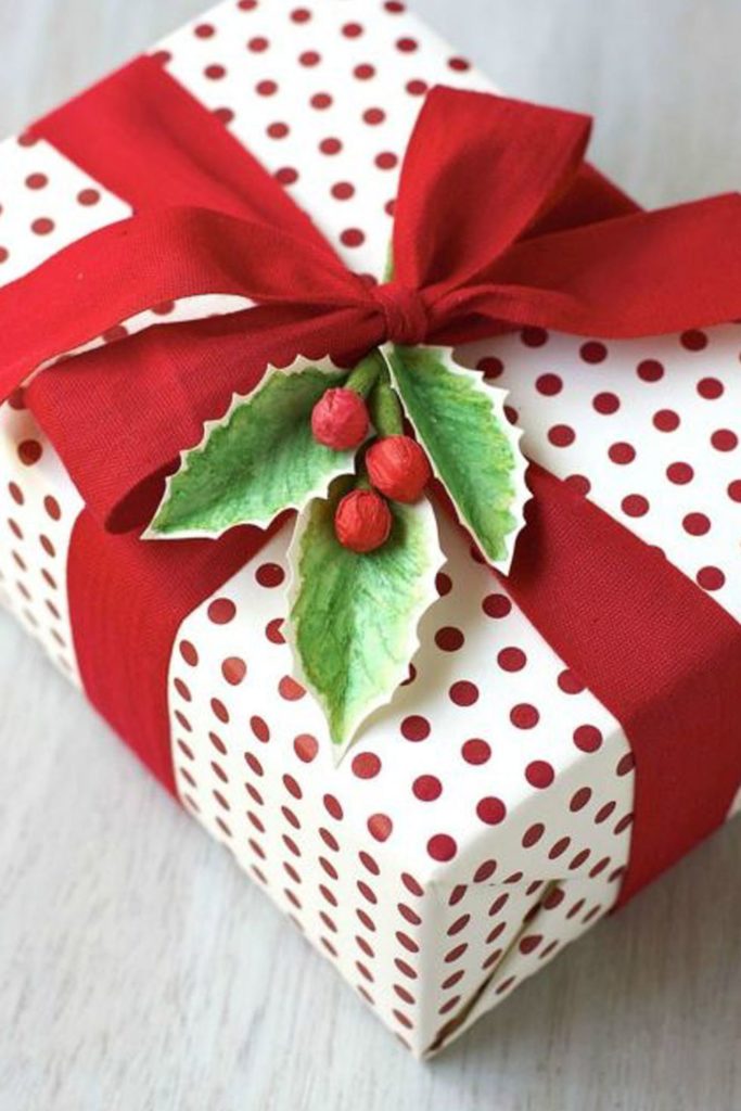 This gift wrap is colorful red and white polka dots, with red ribbon and holly berries.