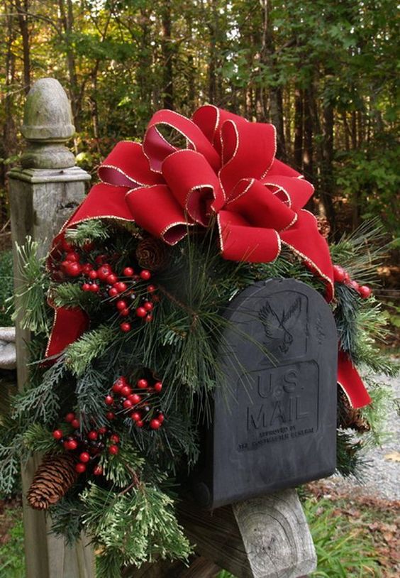 This Christmas mailbox is decked out with a giant red bow, hollie berries, and beautiful pine branches