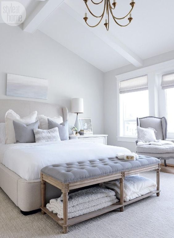 This bright white master bedroom mixes a neutral color scheme with cozy antique furniture for style and comfort