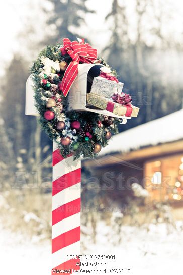 This Christmas mailbox looks like the marker of the north pole with a candy cane pole and a decorated Christmas wreath