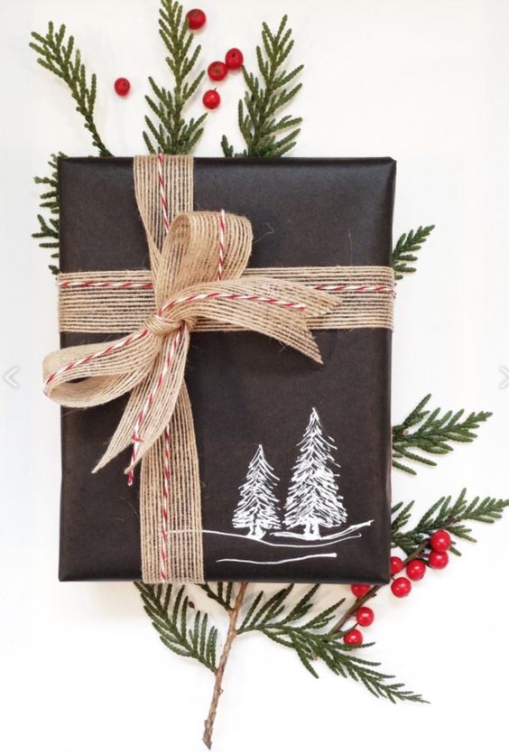 Evergreen branches tucked into holiday twine wrapped around simple black wrapping paper