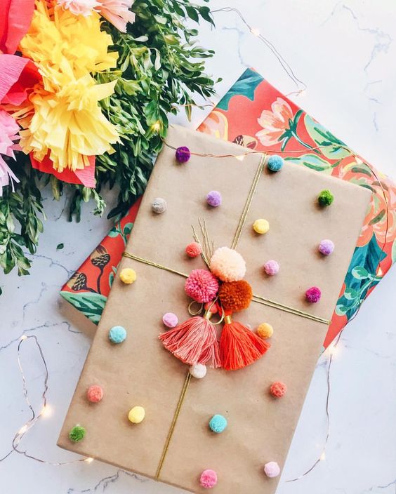 The colorful pom poms on this simple gift wrapping gives this present so much personality