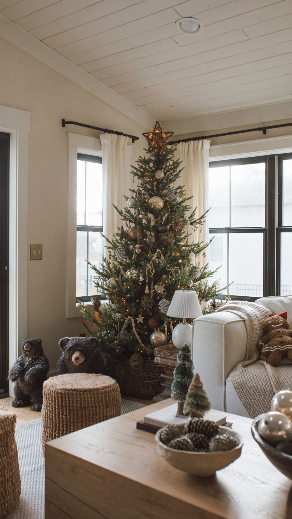 Cozy farmhouse living room with a rustic Christmas tree decorated in warm neutrals, wooden beads, and natural ornaments for a cabin-inspired holiday style.