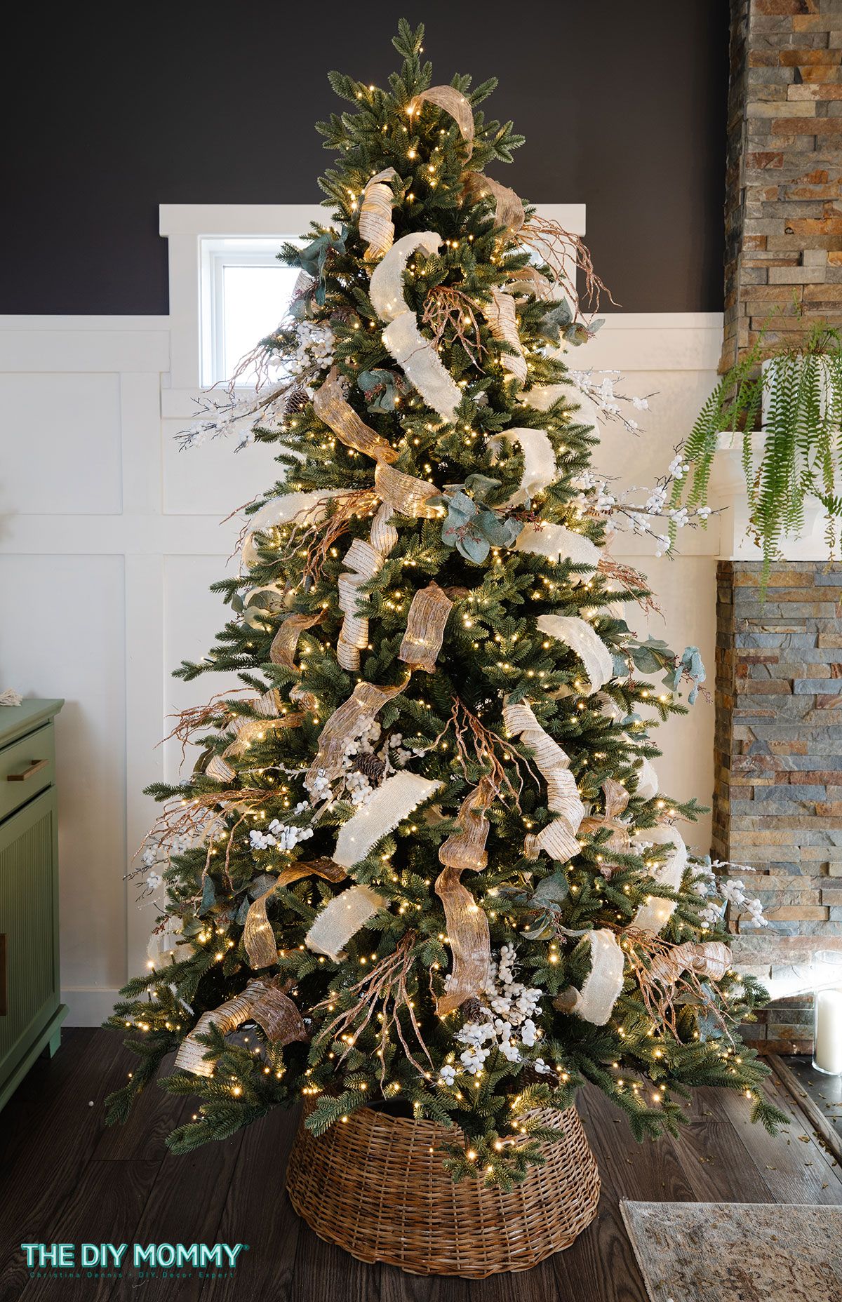 Elegant farmhouse Christmas tree decorated with layered neutral ribbons, gold accents, and natural greenery for a cozy holiday look.