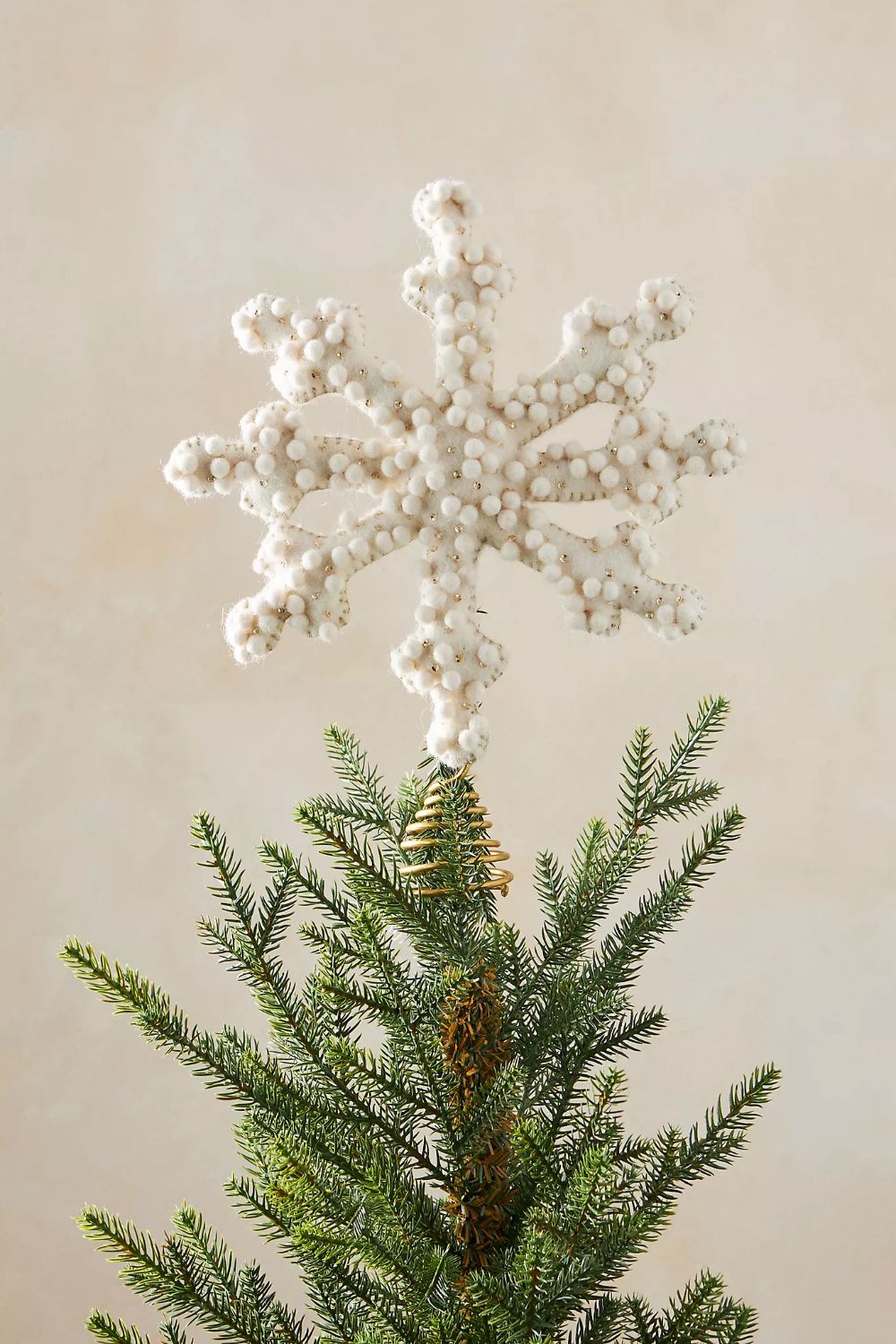 Minimalist Christmas tree with a white textured snowflake topper for a modern, elegant holiday look.