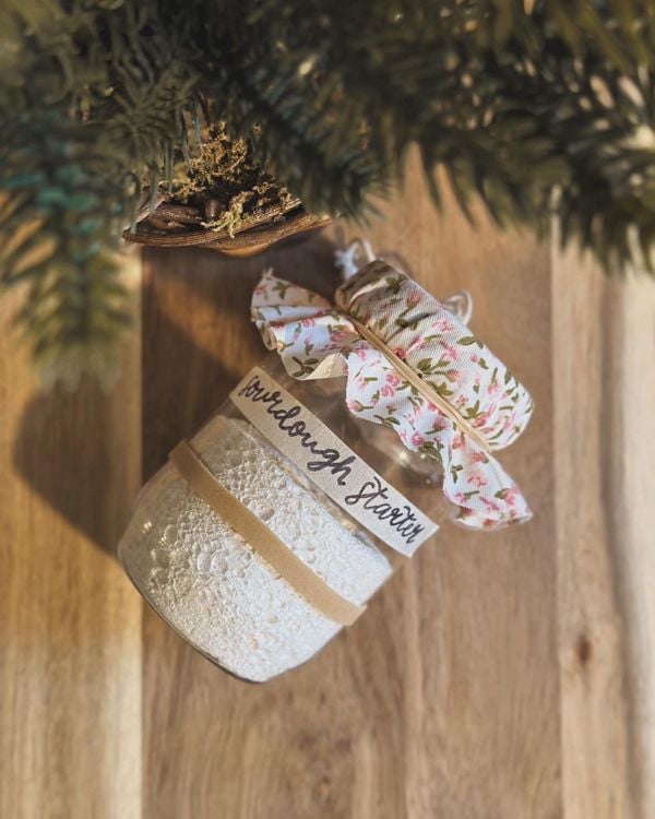 DIY sourdough starter Mason jar gift with a fabric lid and handwritten label, a thoughtful homemade gift for bakers.