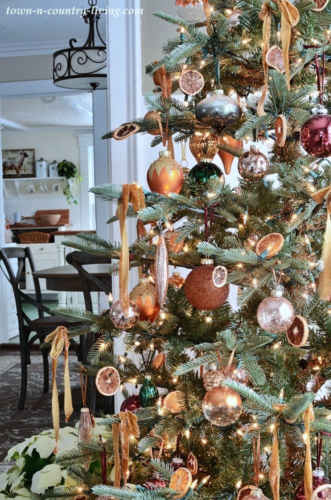 Christmas tree decorated with dried oranges, velvet ribbons, and mixed metallic ornaments for a blend of vintage and modern holiday style.